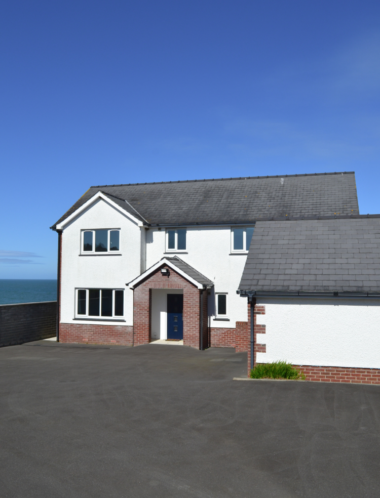 The external house view as you arrive at the property. A large tarmac driveway with a white and brick exterior.